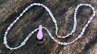 a necklace with purple beads and a purple pendant