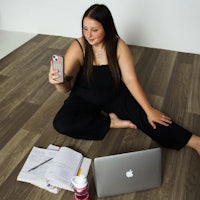 a woman sitting on the floor with her phone and notebook