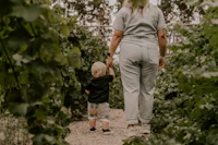 a woman and a child walking through a vineyard