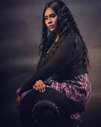 a woman wearing a purple skirt and black hat