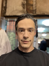 a man in a black shirt is standing in front of a mirror