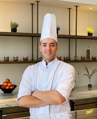 a chef standing in front of a counter with his arms crossed