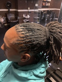 a man with dreadlocks sitting in a barber shop