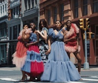 a group of women in colorful dresses standing on a street