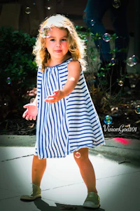a little girl in a blue and white striped dress