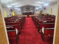 the inside of a church with red carpet and pews