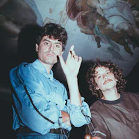 two men standing next to each other in front of a painting