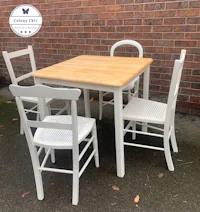 a white dining table and chairs in front of a brick wall