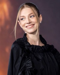 a woman in a black dress smiles in front of a fire