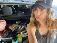 a woman in a hat is standing in the trunk of a car