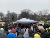 a group of people standing under a tent in a rainy day