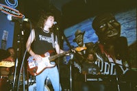 a man playing a guitar in front of a mural