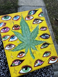 a painting of a marijuana leaf with eyes on it