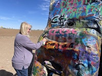 a woman standing next to a car covered in graffiti