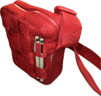 a red cross body bag with a pen in it