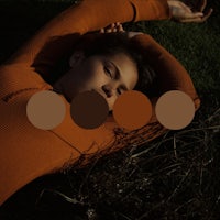 a woman laying in the grass with a brown sweater