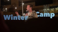a man is standing in front of a stage with the words winter camp