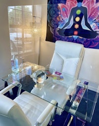 a room with a white desk, chairs and a wall hanging