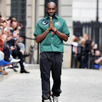a black man in a green shirt walking down the street