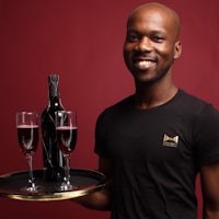 a man holding a tray with two glasses of wine