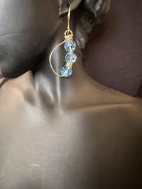 a black mannequin with a blue glass earring