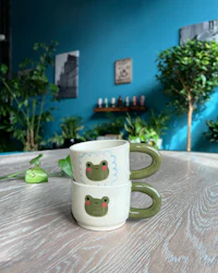 two frog mugs sitting on a wooden table