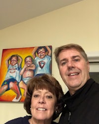a man and woman posing for a photo in front of a painting