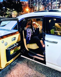 a man sitting in the back seat of a white rolls royce