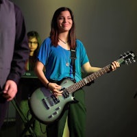 a woman in jeans and a plaid shirt standing on a skateboard
