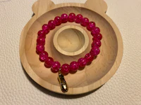 a pink beaded bracelet on a wooden tray
