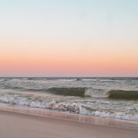 a beach with waves at sunset
