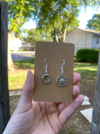 a person holding up a pair of silver earrings
