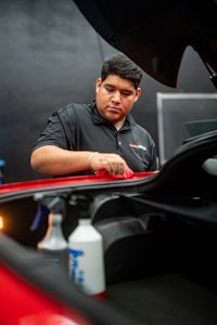 a man cleaning a red sports car
