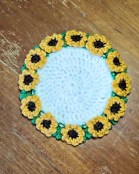 a crocheted sunflower coaster on a wooden table