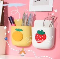 a pink wall with fruit and pens hanging on it