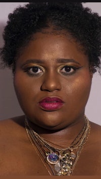 a black woman wearing a gold necklace and pink lipstick
