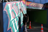 a woman painting a mural on the side of a building