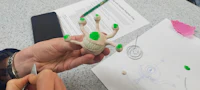 a person is making a clay toy with green eyes