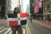 a woman holding a dominican flag on a city street