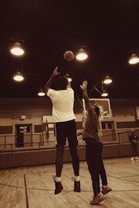 two people playing basketball in a gym