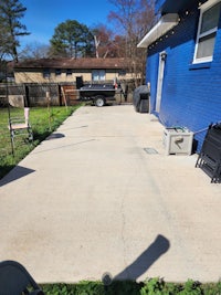 a backyard with a concrete patio and a lawn mower