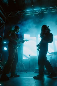 two people playing guitar on stage in a dark room