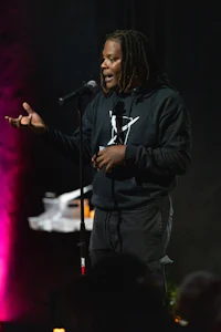 a man with dreadlocks standing in front of a microphone
