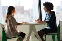 two women talking at a table in an office