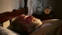 a man sleeping in a bed with a beard