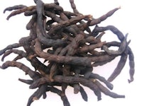 a pile of black tea leaves on a white background