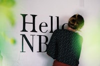 a woman painting a hello nb sign on a wall