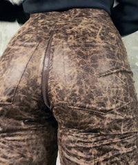the back view of a woman wearing brown leather pants