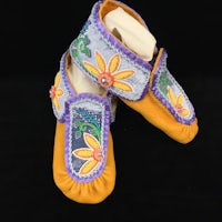 a pair of yellow and purple moccasins with flowers on them