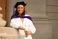 a woman in a graduation gown and hat is posing for a photo